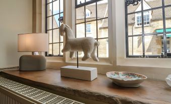a room with a large window , white horse statue , and a lamp on a wooden table at The Bull Hotel