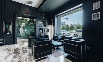 a modern office space with black leather furniture , a large window , and a car parked outside at Hotel Continental