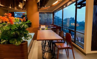 a modern dining room with wooden tables and chairs , as well as a large window overlooking the city at Hotel Cianjur Cipanas