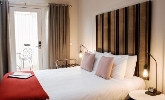 a bed with white sheets and pillows is in a room with a striped headboard at Alexandra Place