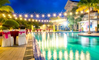 a large swimming pool surrounded by tables and chairs , with a beautiful nighttime view of the surrounding area at Novilla Boutique Resort