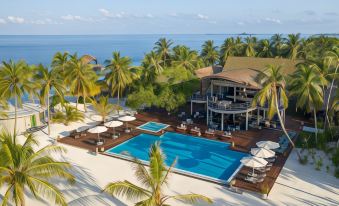 aerial view of a resort with a large pool surrounded by palm trees and lounge chairs at Outrigger Maldives Maafushivaru Resort