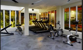 a well - lit gym with various exercise equipment , including treadmills and stationary bikes , arranged in a spacious space at Ppt Muar Hotel