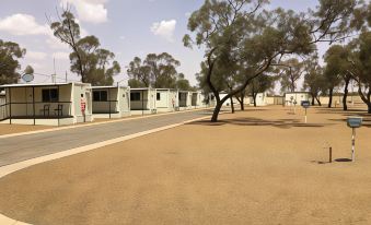 a sandy road with several mobile homes on both sides , some of which have been remodeled at Broken Hill Tourist Park