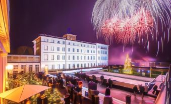 a large building with a christmas tree in front of it and fireworks going off behind at Grand Hotel Heiligendamm - the Leading Hotels of the World