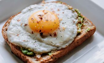 a slice of toast topped with an egg and avocado , sitting on a plate with some seasoning at The Upper House Hotel