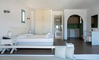 a modern bedroom with a white bed , wooden wardrobe , and a small kitchenette in the background at Aeri