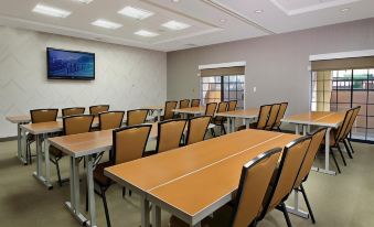 a classroom setting with multiple tables and chairs arranged in rows , along with a television mounted on the wall at SpringHill Suites Madera