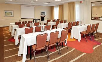 a conference room with tables and chairs , a projector screen , and a red carpeted floor at Hilton Garden Inn Plymouth