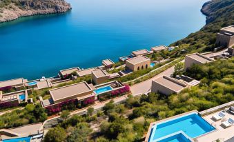 a resort with a pool and multiple buildings is nestled near the ocean , providing a serene view of the surrounding landscape at Daios Cove Luxury Resort & Villas