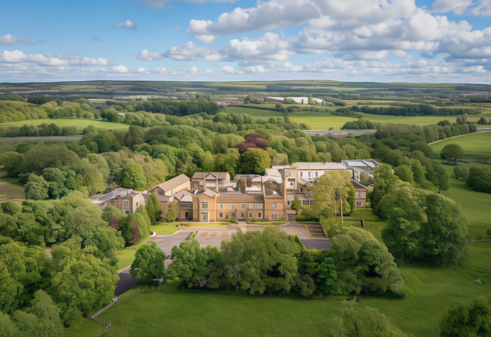 aerial view of a large mansion surrounded by trees , with a lake visible in the background at Mercure Blackburn Dunkenhalgh Hotel & Spa