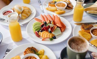 a table is set with a variety of breakfast foods , including fruits , breads , and beverages at Paradise Country Farmstay