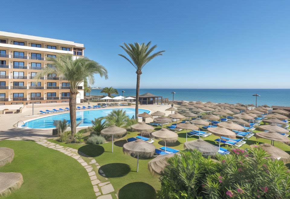 a large resort with a pool surrounded by palm trees and a beach in the background at Vik Gran Hotel Costa del Sol