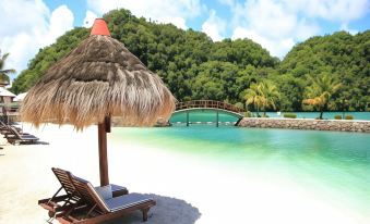 a tropical beach with clear blue water , white sand , and a thatched umbrella on a sunny day at Palau Hotel