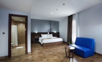 a hotel room with a king - sized bed , hardwood floors , and a blue couch in the corner at Horison Express Sentani