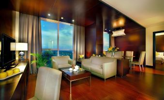 a spacious living room with wooden floors and large windows , featuring comfortable furniture and a view of the city at ASTON Purwokerto Hotel & Convention Center