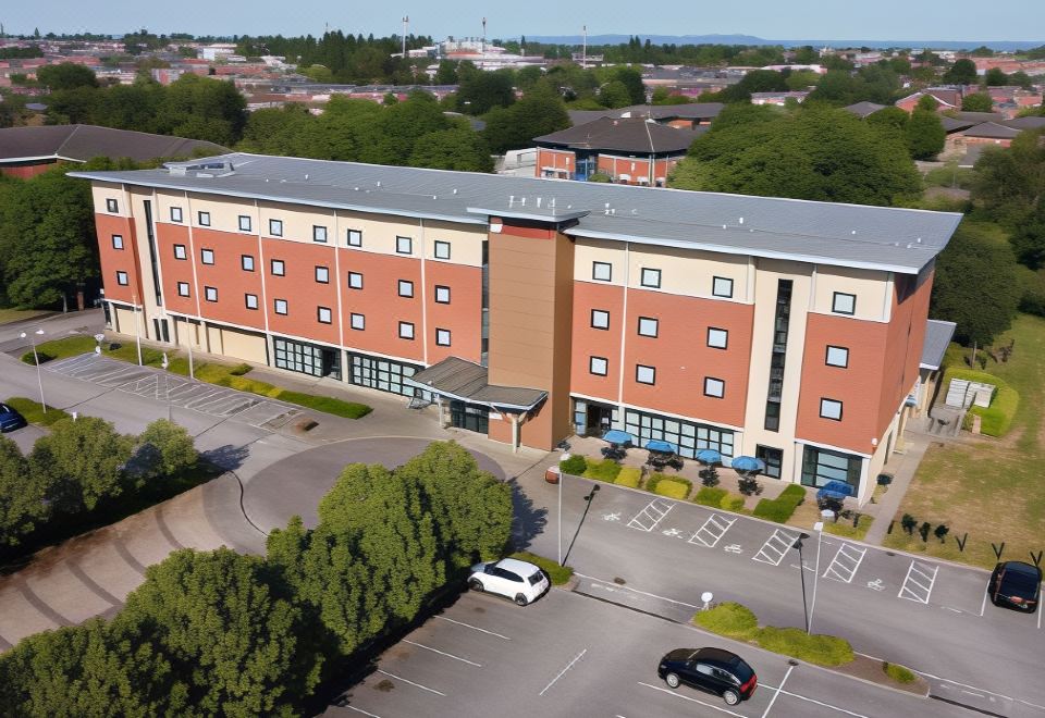 an aerial view of a large hotel with multiple floors , surrounded by trees and parked cars at Ramada Plaza by Wyndham Wrexham
