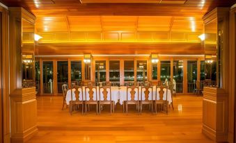 a large dining room with wooden floors and tables set for a meal , surrounded by windows and chairs at Parn Dhevi Riverside Resort & Spa