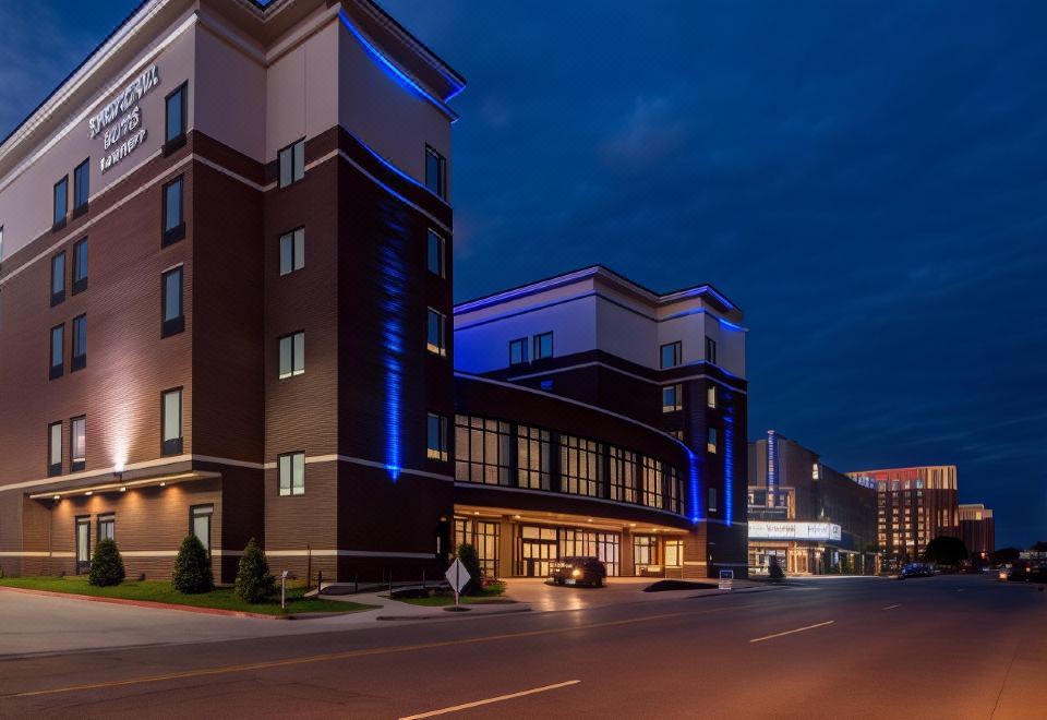 a modern hotel building at night , with its blue lights illuminating the exterior and cars parked outside at SpringHill Suites Oklahoma City Downtown/Bricktown