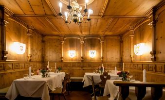 a restaurant with wooden walls and ceiling , multiple tables set for dining , white tablecloths , and wine glasses at Hotel Sailer