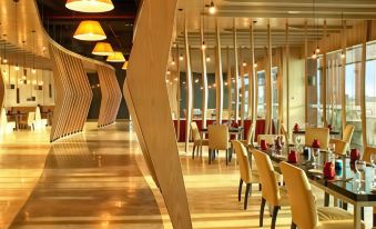 a modern restaurant with wooden floors , yellow chairs , and red accents , lit by hanging lights at Duyong Marina & Resort