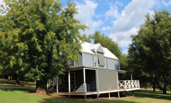 a modern , two - story house with a wooden deck and green grass , under a clear blue sky at Abby's Cottages