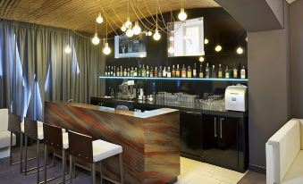 a modern bar with a wooden counter , multiple stools , and various bottles of alcohol on the shelves at Pure White