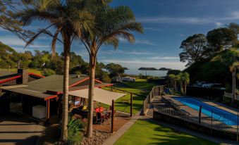 a luxurious resort with a pool , umbrellas , and palm trees , overlooking the ocean and palm trees at Anglers Lodge
