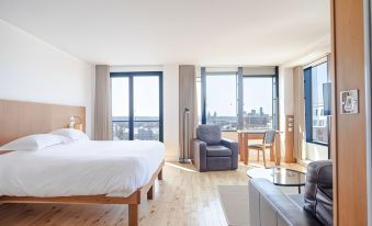 a modern hotel room with wooden flooring , large windows offering city views , and comfortable furniture at Hope Street Hotel