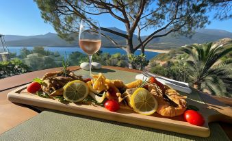 a wooden platter filled with a variety of food items , including fish , shrimp , and vegetables , placed on a dining table at A’mare Corsica Seaside Small Resort