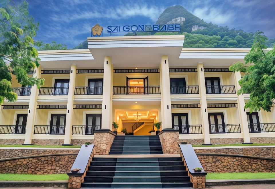 the exterior of a large , yellow - colored building with blue lettering and stone stairs leading up to it at Saigon-Ba Be Resort