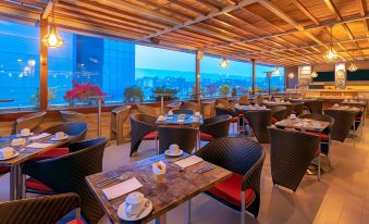 a modern restaurant with wooden tables , chairs , and blue cushions , offering a view of the city through large windows at Sonesta Hotel Arequipa