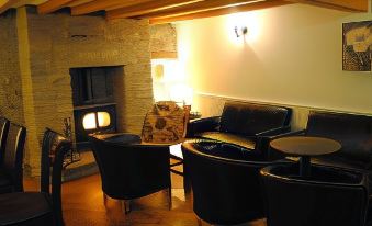 a cozy living room with multiple black leather couches and chairs arranged around a fireplace at The Village Inn