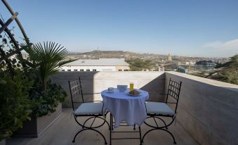 a small dining table with chairs and a white tablecloth , set on a balcony overlooking a cityscape at Citrus Hotel