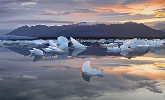a large group of white icebergs floating in the water with mountains in the background at Fosshotel Glacier Lagoon