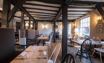 a dining room with wooden tables and chairs , along with a kitchen in the background at The Crown