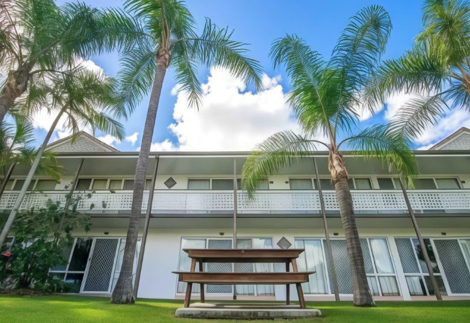 a beautiful house with multiple balconies and a bench in front of it , surrounded by palm trees at Bay of Palms