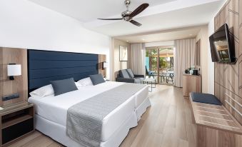 a large bed with a blue headboard and white linens is in a room with wooden floors at Hotel Riu Palace Oasis