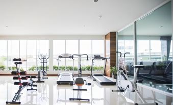 a well - equipped gym with various exercise equipment , including treadmills and weight machines , near large windows that offer views of the outdoors at Bay Hotel Srinakarin