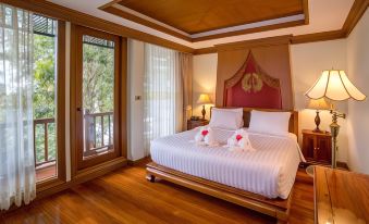 a spacious bedroom with a large bed and two red swans on it , creating a romantic atmosphere at RK Riverside Resort & Spa (Reon Kruewal)