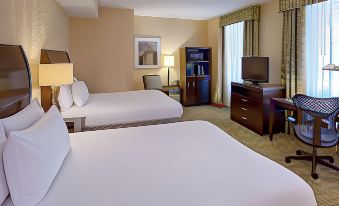 a hotel room with two beds , a desk , and a tv , all neatly arranged in a modern style at Hilton Garden Inn Jackson Downtown