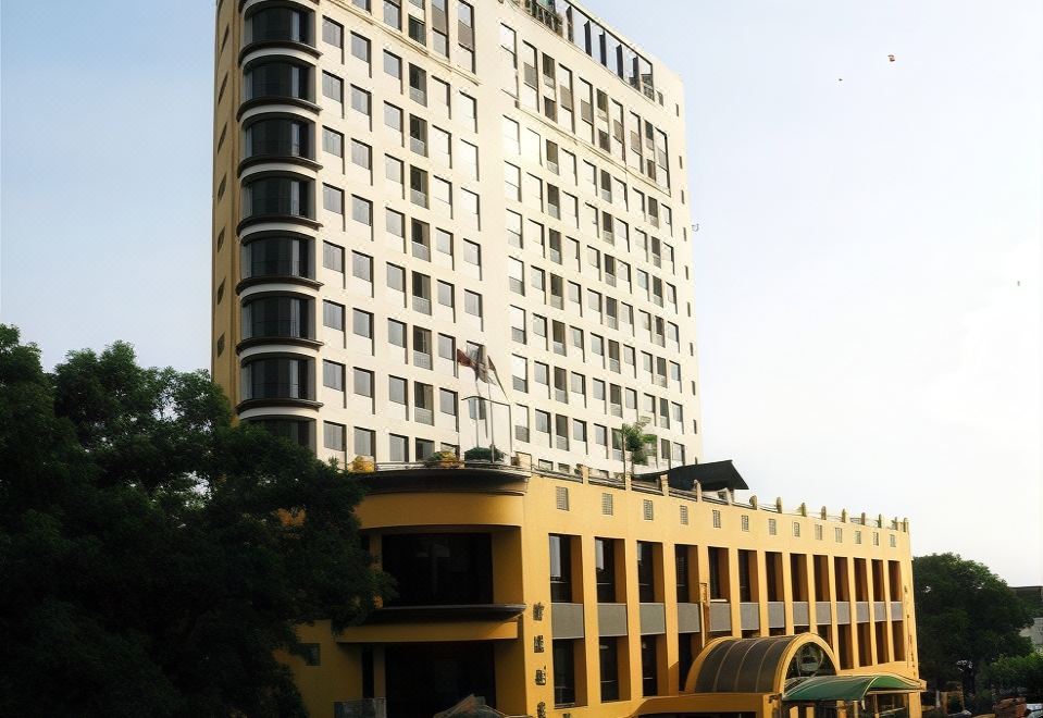 a large , modern building with a yellow and white facade is surrounded by trees on a street at Good Hope Hotel