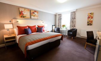 a large bed with orange and white pillows is in a room with purple carpeting at Caledonian Hotel
