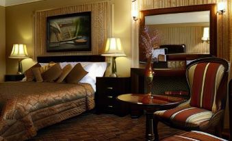 a luxurious hotel room with a king - sized bed , a chair , and a painting on the wall at Riverside Inn