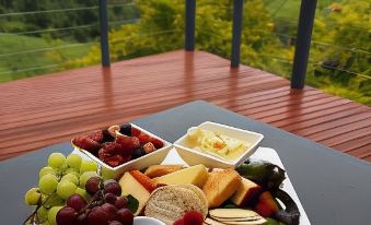 a wooden table with a variety of fruits and cheeses , including grapes , strawberries , and cheese cubes at Top of the Hill