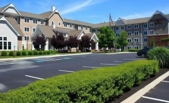 a large , modern hotel building with multiple stories and balconies , surrounded by lush green trees and a parking lot filled with cars at Residence Inn Richmond Chester