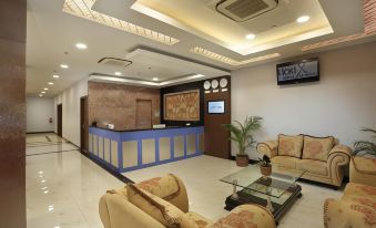 a modern hotel lobby with a reception desk , comfortable seating area , and a television mounted on the wall at Horison Express Sentani