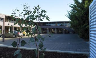 a building with a large entrance and trees in front of it , set against a clear blue sky at Morwell Motel