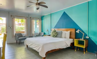 a bedroom with a large bed , blue and green walls , and a ceiling fan , along with a living room area at Selina Jaco