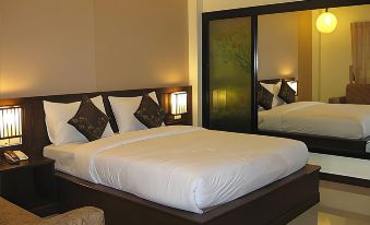 a large bed with white linens and black pillows is situated in a room with two lamps at Palm Sweet Resort